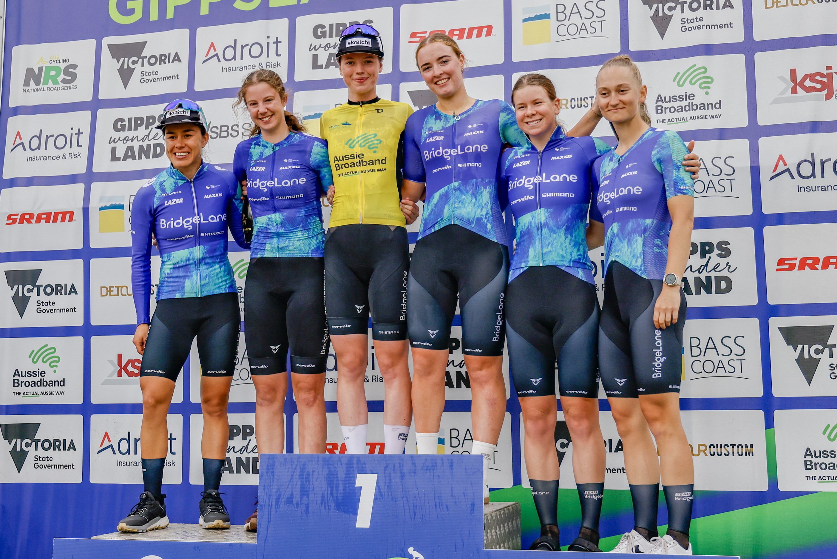 Gina Ricardo, Katelyn Nicholson, Keely Bennett, Lillee Pollock, Talia Appleton,  Amanda Poulsen (L-R) of Team BridgeLane, cyclists, on the podium of the 2024 Tour of Gippsland part of the 2024 AusCycling National Road Series NRS